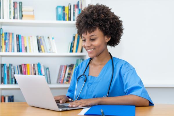 A nursing student sits in front of her laptop studying online with one of the regional universities in Australia